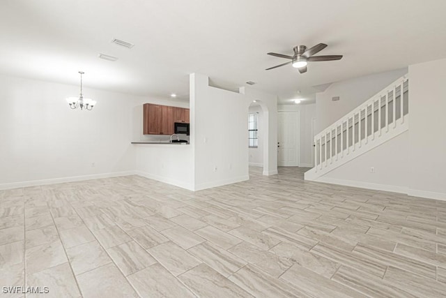 unfurnished living room with ceiling fan with notable chandelier