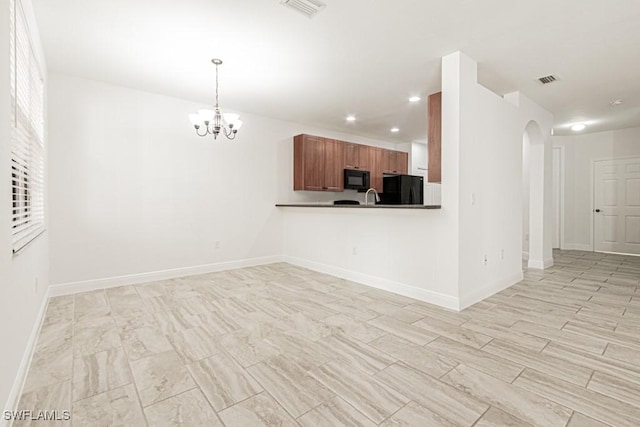 unfurnished living room featuring sink and a notable chandelier