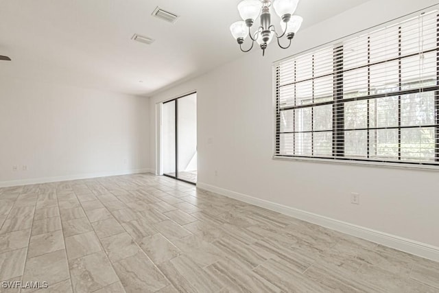 unfurnished room with a notable chandelier