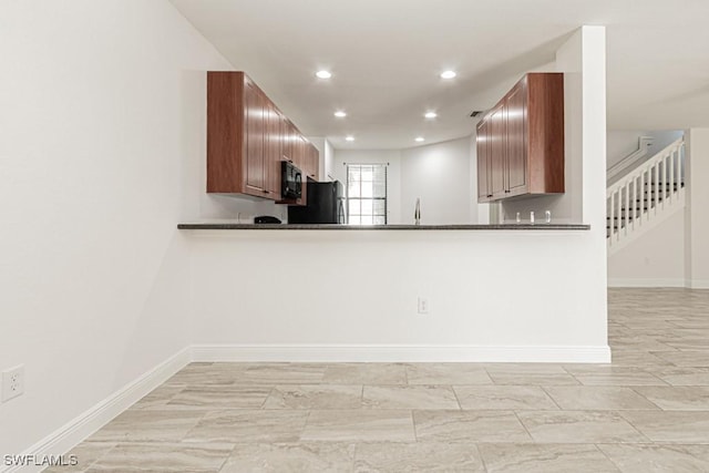 kitchen with dark stone countertops, kitchen peninsula, sink, and black appliances