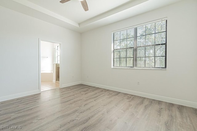 unfurnished room featuring ceiling fan, a tray ceiling, and light hardwood / wood-style flooring