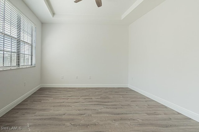 unfurnished room with a tray ceiling, light hardwood / wood-style flooring, and ceiling fan