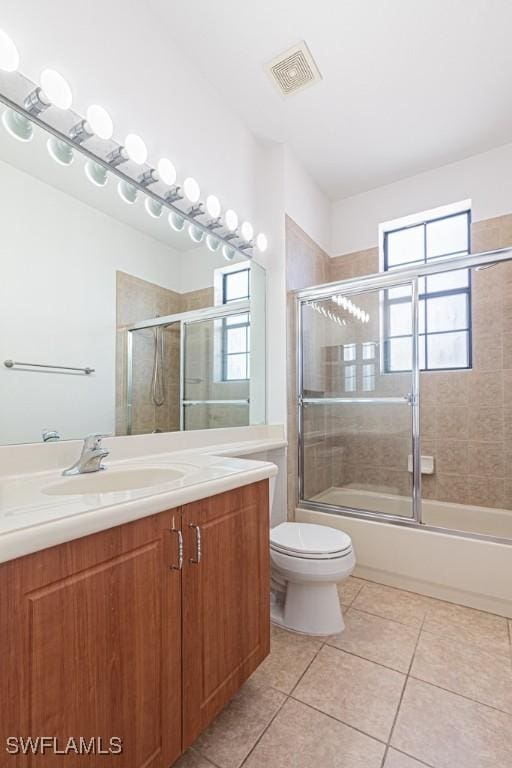 full bathroom with tile patterned flooring, vanity, enclosed tub / shower combo, and toilet