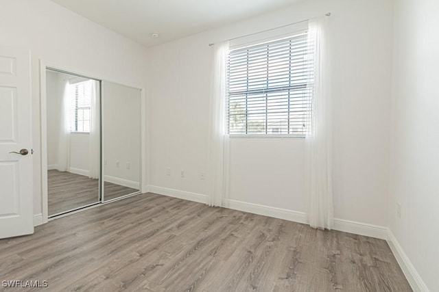 unfurnished bedroom with light hardwood / wood-style floors and a closet