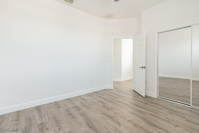 unfurnished bedroom featuring ceiling fan, a closet, and light wood-type flooring