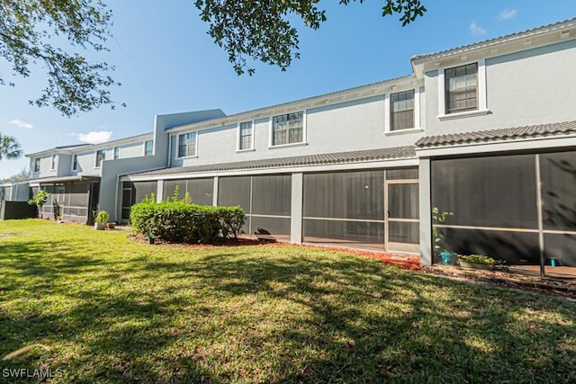 rear view of property with a sunroom and a yard