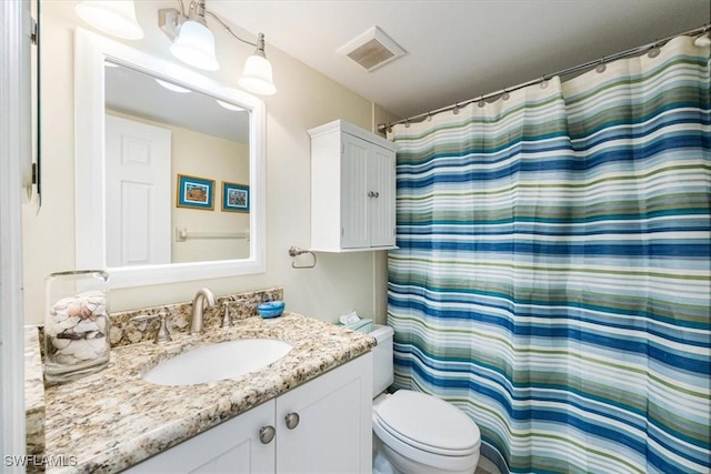 bathroom featuring toilet, a shower with curtain, visible vents, and vanity