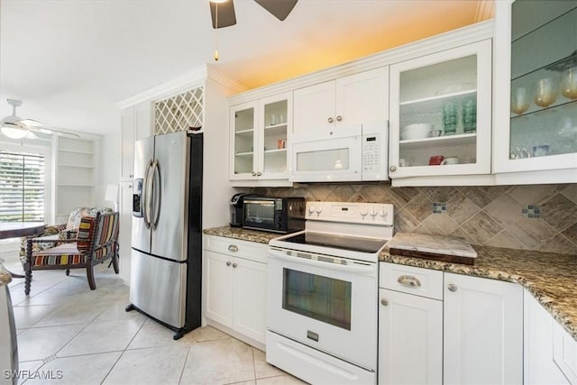 kitchen featuring white appliances, dark stone countertops, glass insert cabinets, and white cabinetry