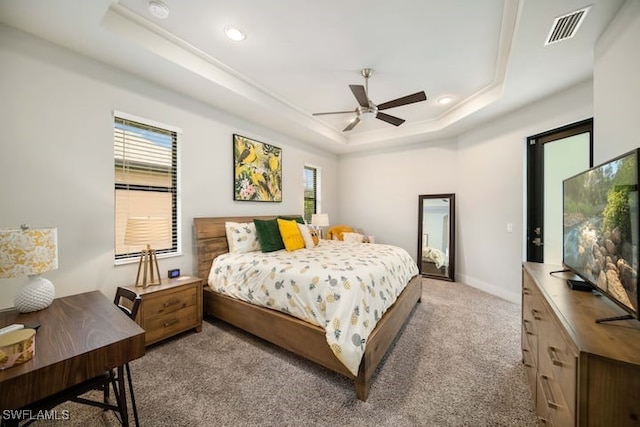 bedroom featuring a raised ceiling, light colored carpet, and ceiling fan