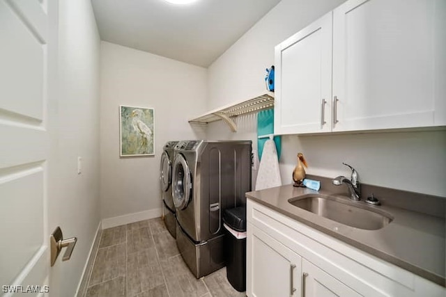 clothes washing area with cabinets, washer and clothes dryer, and sink