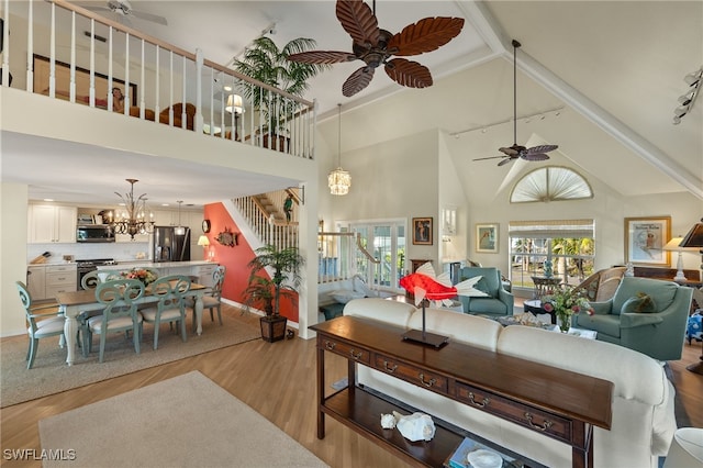 living room featuring ceiling fan with notable chandelier, track lighting, high vaulted ceiling, and light wood-type flooring