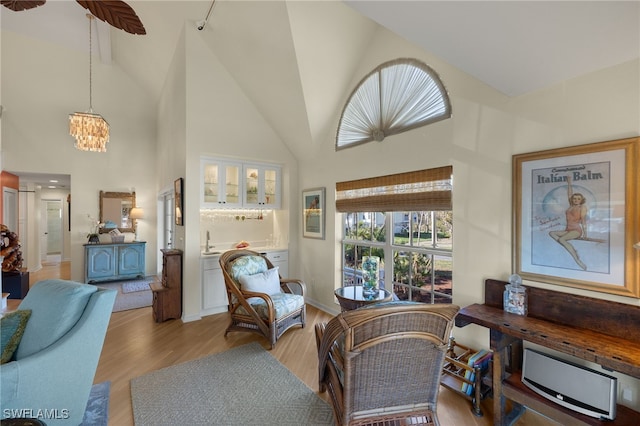 living area featuring an inviting chandelier, high vaulted ceiling, and light wood-type flooring