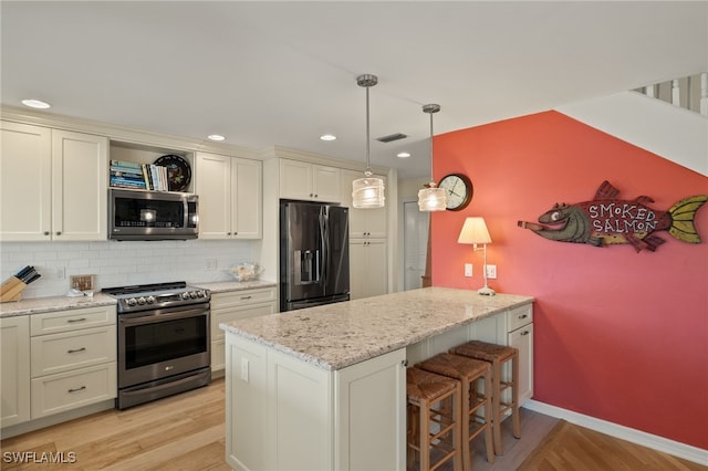 kitchen with light stone counters, appliances with stainless steel finishes, decorative backsplash, and pendant lighting