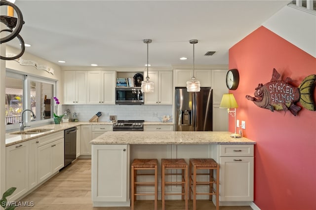 kitchen with stainless steel appliances, hanging light fixtures, backsplash, and light stone counters