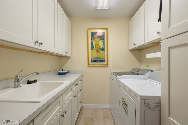 clothes washing area featuring independent washer and dryer, cabinets, sink, and light wood-type flooring