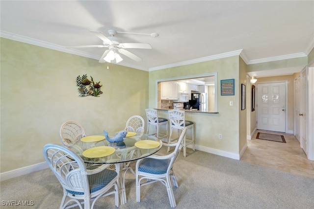 carpeted dining room with ornamental molding and ceiling fan