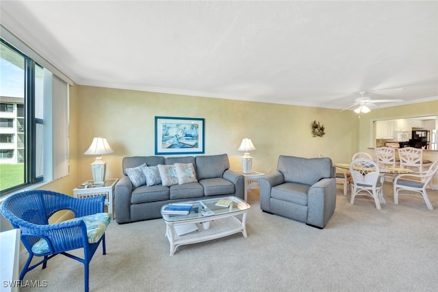 carpeted living room featuring ornamental molding and ceiling fan