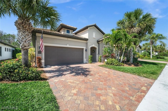 mediterranean / spanish home featuring decorative driveway, an attached garage, and stucco siding