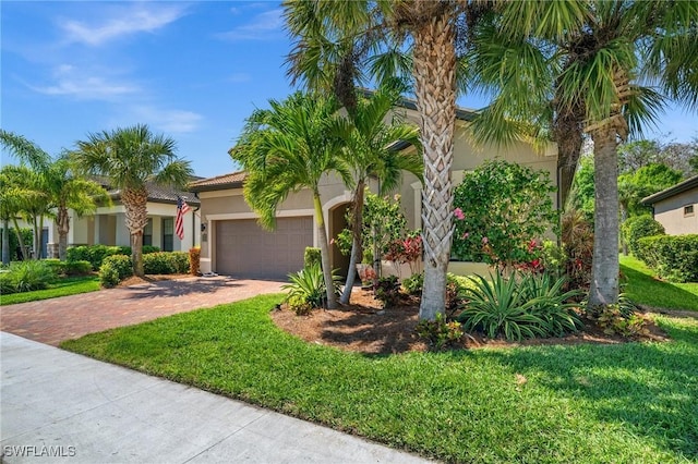 view of front facade with a front lawn, decorative driveway, an attached garage, and stucco siding