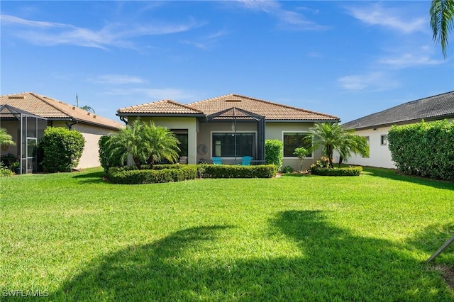 back of property featuring a tiled roof, a lawn, and stucco siding