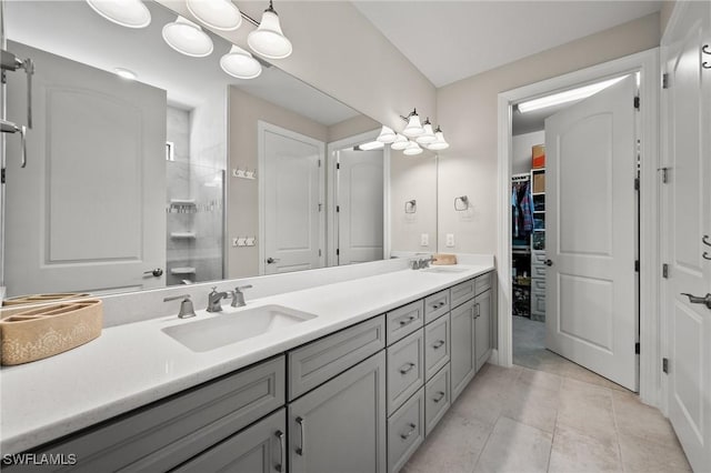 full bath featuring double vanity, a walk in closet, a sink, and tile patterned floors