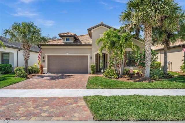 mediterranean / spanish-style house featuring decorative driveway, a tiled roof, an attached garage, and stucco siding