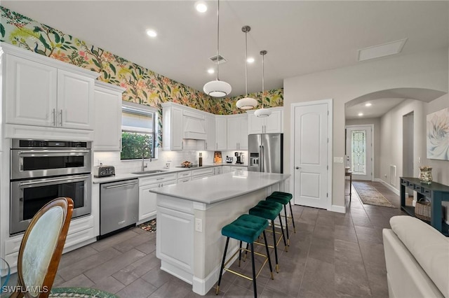 kitchen with arched walkways, a breakfast bar area, a sink, visible vents, and appliances with stainless steel finishes