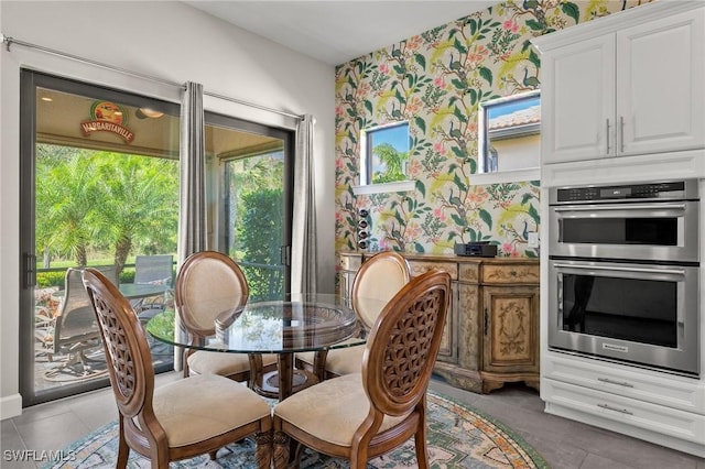 dining room featuring light tile patterned floors and wallpapered walls