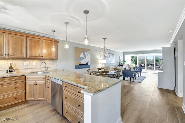 kitchen with light stone counters, stainless steel dishwasher, kitchen peninsula, and sink