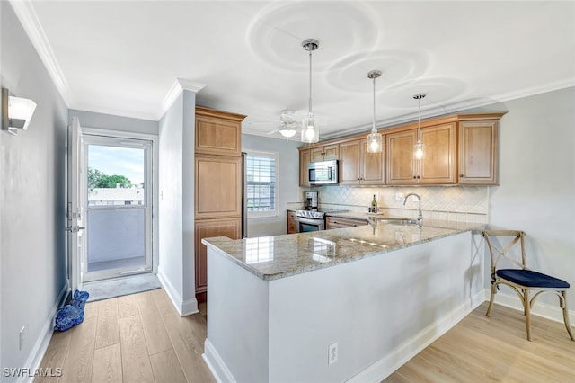 kitchen with sink, light stone counters, decorative light fixtures, kitchen peninsula, and stainless steel appliances