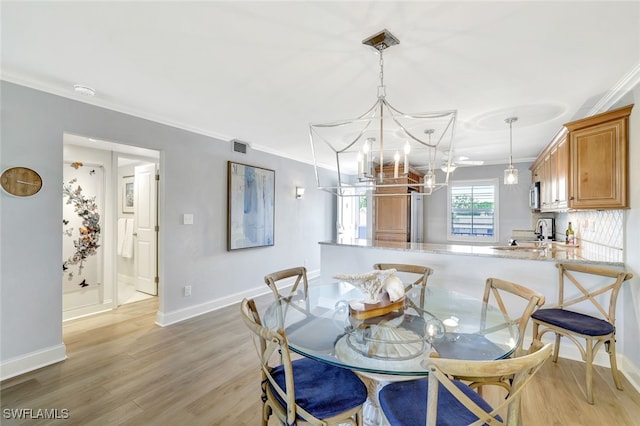 dining area with ornamental molding, sink, a chandelier, and light hardwood / wood-style floors