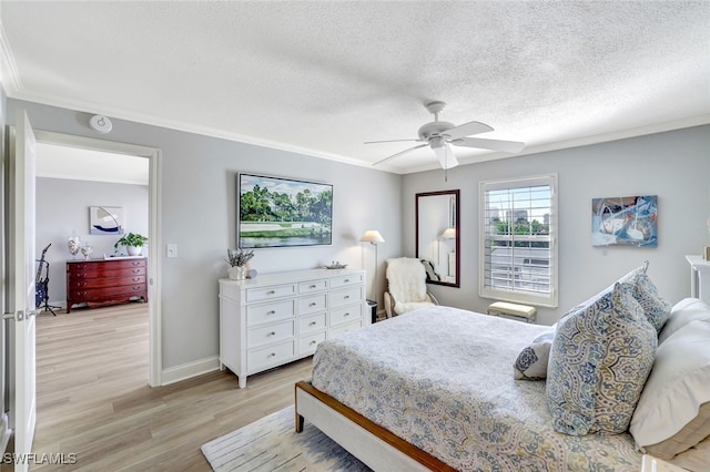 bedroom with ceiling fan, light hardwood / wood-style flooring, ornamental molding, and a textured ceiling