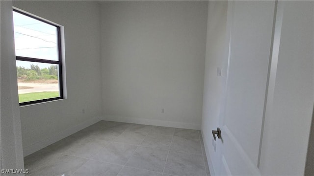 spare room with baseboards and light tile patterned flooring