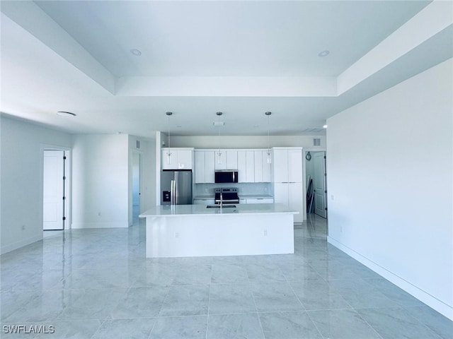 kitchen featuring a tray ceiling, stainless steel appliances, light countertops, a kitchen island with sink, and a sink