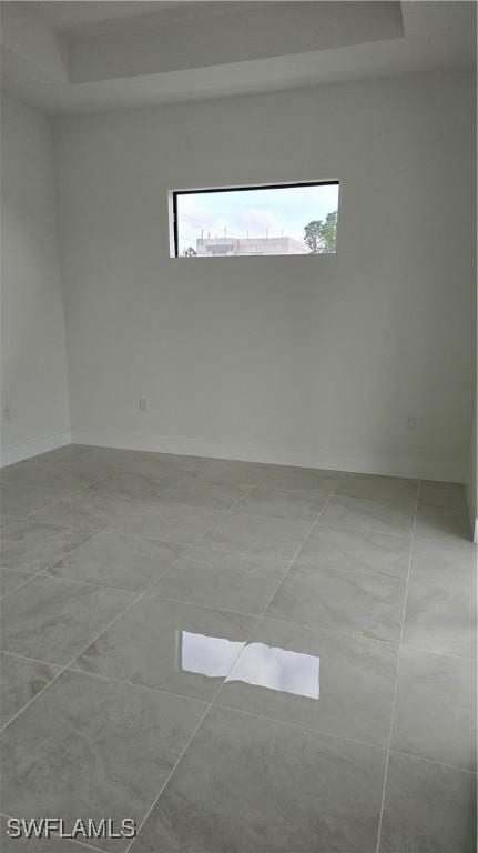 unfurnished room with a raised ceiling and baseboards