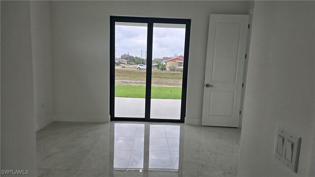 spare room with baseboards and light tile patterned floors