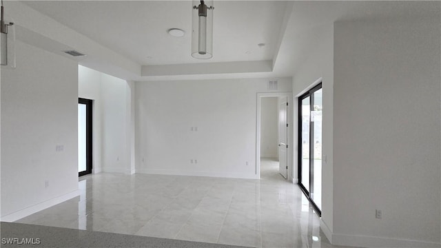 spare room featuring baseboards, visible vents, and a raised ceiling