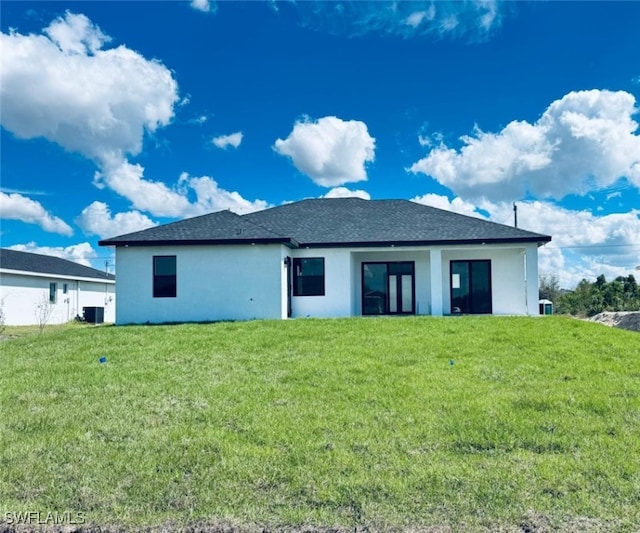 rear view of house featuring stucco siding and a yard