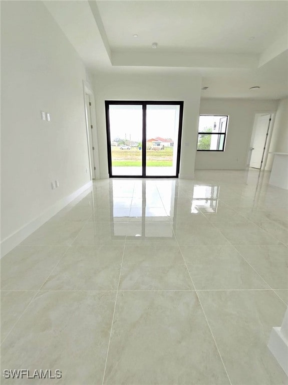 unfurnished room featuring a raised ceiling and baseboards