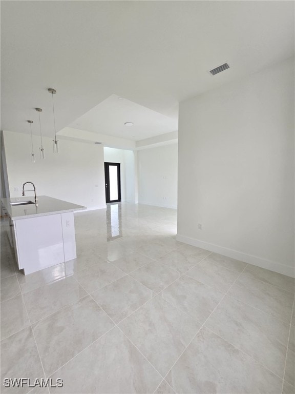 unfurnished room featuring baseboards, visible vents, and a sink