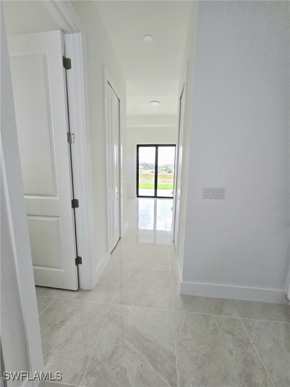 hallway featuring light tile patterned flooring and baseboards