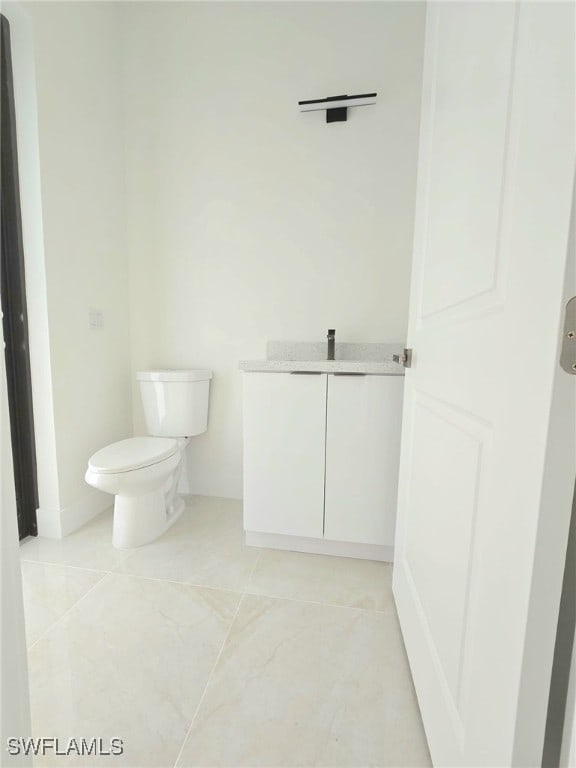 bathroom with toilet, tile patterned floors, and vanity