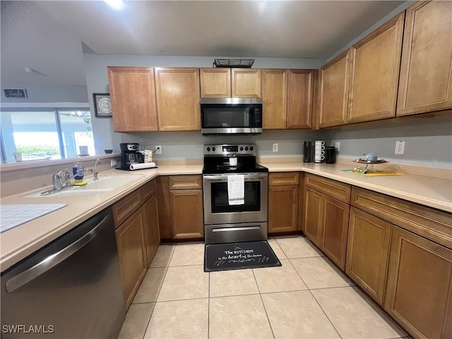 kitchen with appliances with stainless steel finishes, light tile patterned floors, and light countertops