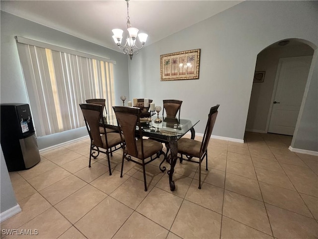 dining area with arched walkways, a chandelier, light tile patterned flooring, baseboards, and vaulted ceiling