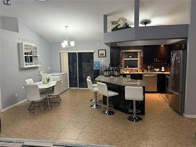 kitchen featuring lofted ceiling, dark stone counters, a kitchen breakfast bar, pendant lighting, and stainless steel appliances