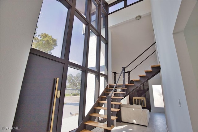 stairway with a towering ceiling, a wealth of natural light, and expansive windows