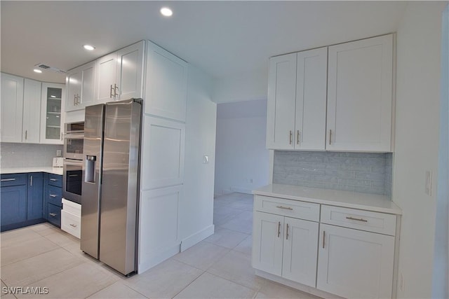 kitchen featuring white cabinetry, backsplash, light tile patterned floors, and appliances with stainless steel finishes