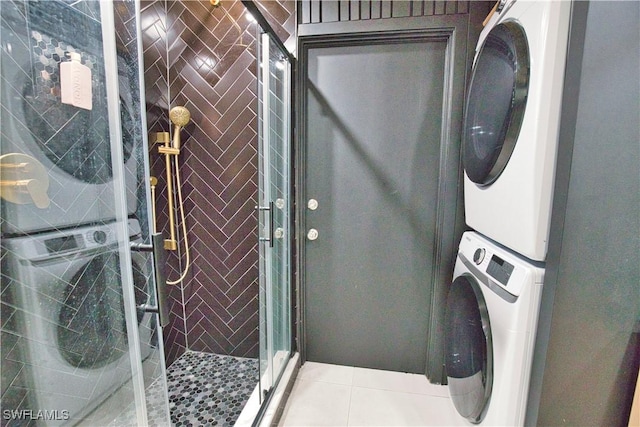 clothes washing area featuring stacked washer and dryer and light tile patterned flooring