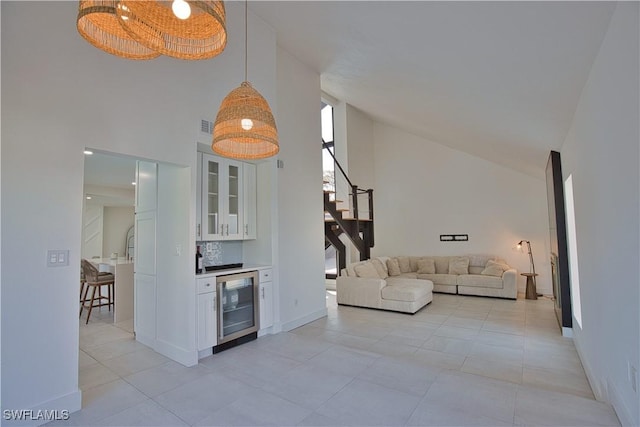 tiled living room featuring wine cooler, bar, and high vaulted ceiling