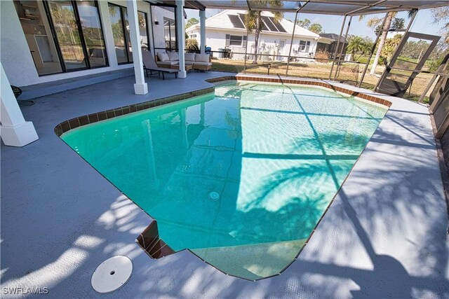 view of pool featuring glass enclosure and a patio area